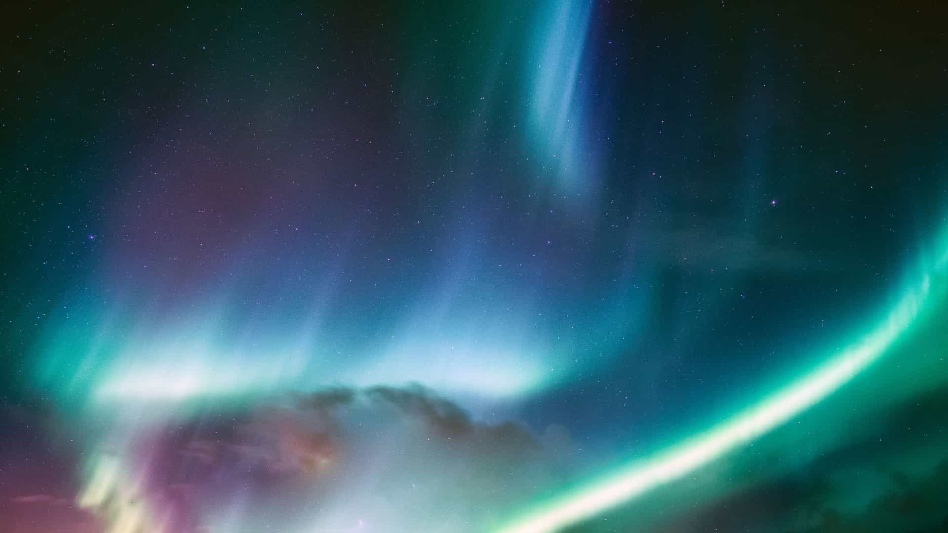 Vibrant aurora borealis over the Arctic Circle, with green, blue, and purple lights dancing across the night sky—an awe-inspiring sight for Viking Expedition Cruise travelers.