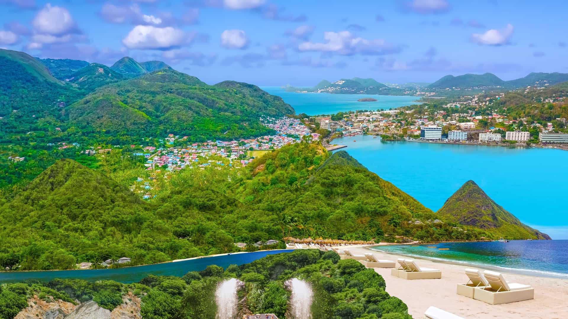 Scenic coastal view of Saint Lucia in the Caribbean, featuring lush green mountains, a turquoise bay, and a sandy beach with lounge chairs—ideal for Viking Expedition Cruise travelers seeking tropical exploration.