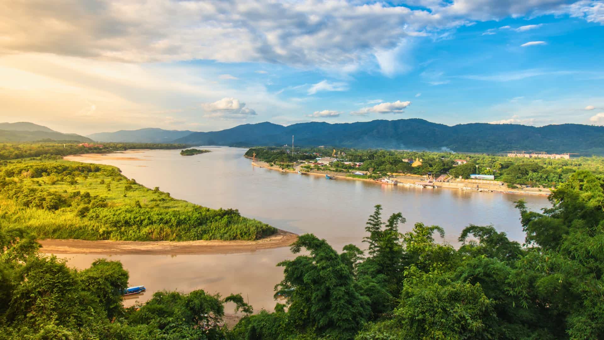 The wide and scenic Mekong River flowing through the lush, green landscape of Southeast Asia, a breathtaking view from a Viking River cruise.