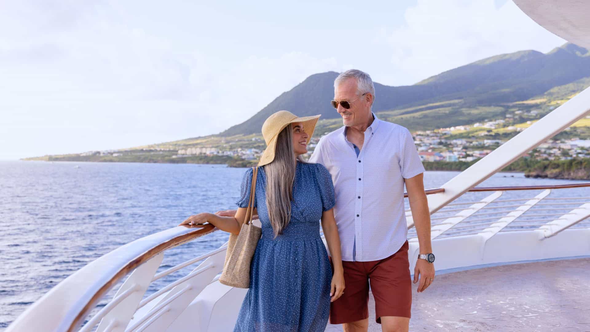 A happy couple on the deck of a Windstar cruise ship, enjoying a scenic view during a transatlantic voyage.
