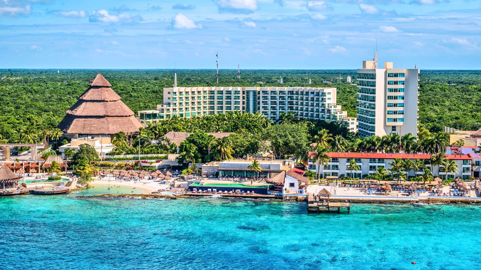 Resorts and a thatched pyramid-like building on the coast of Cozumel, Mexico, a popular port of call for a Windstar cruise in the Western Caribbean.