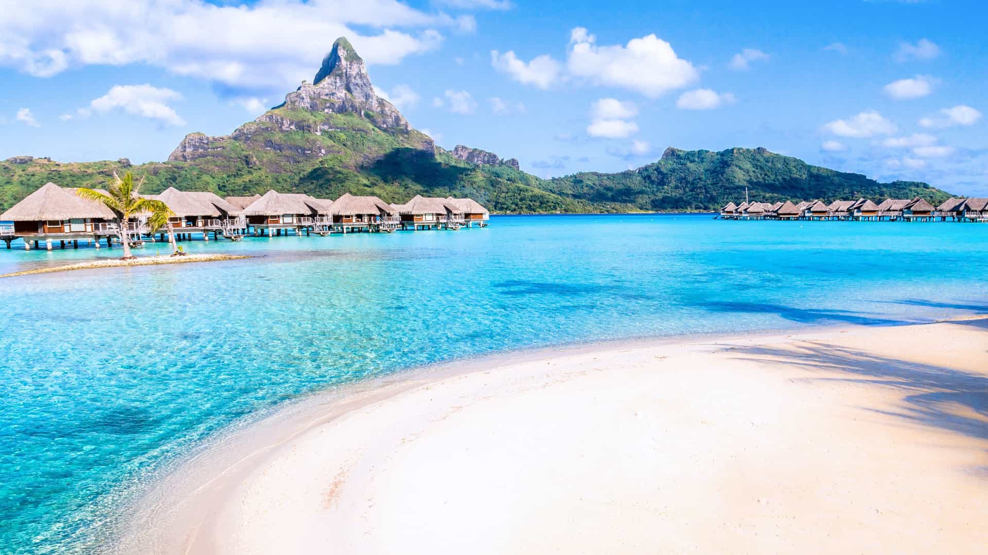 Overwater bungalows and a sandy beach in Bora Bora, Tahiti, a picturesque Windstar cruise destination in the South Pacific.