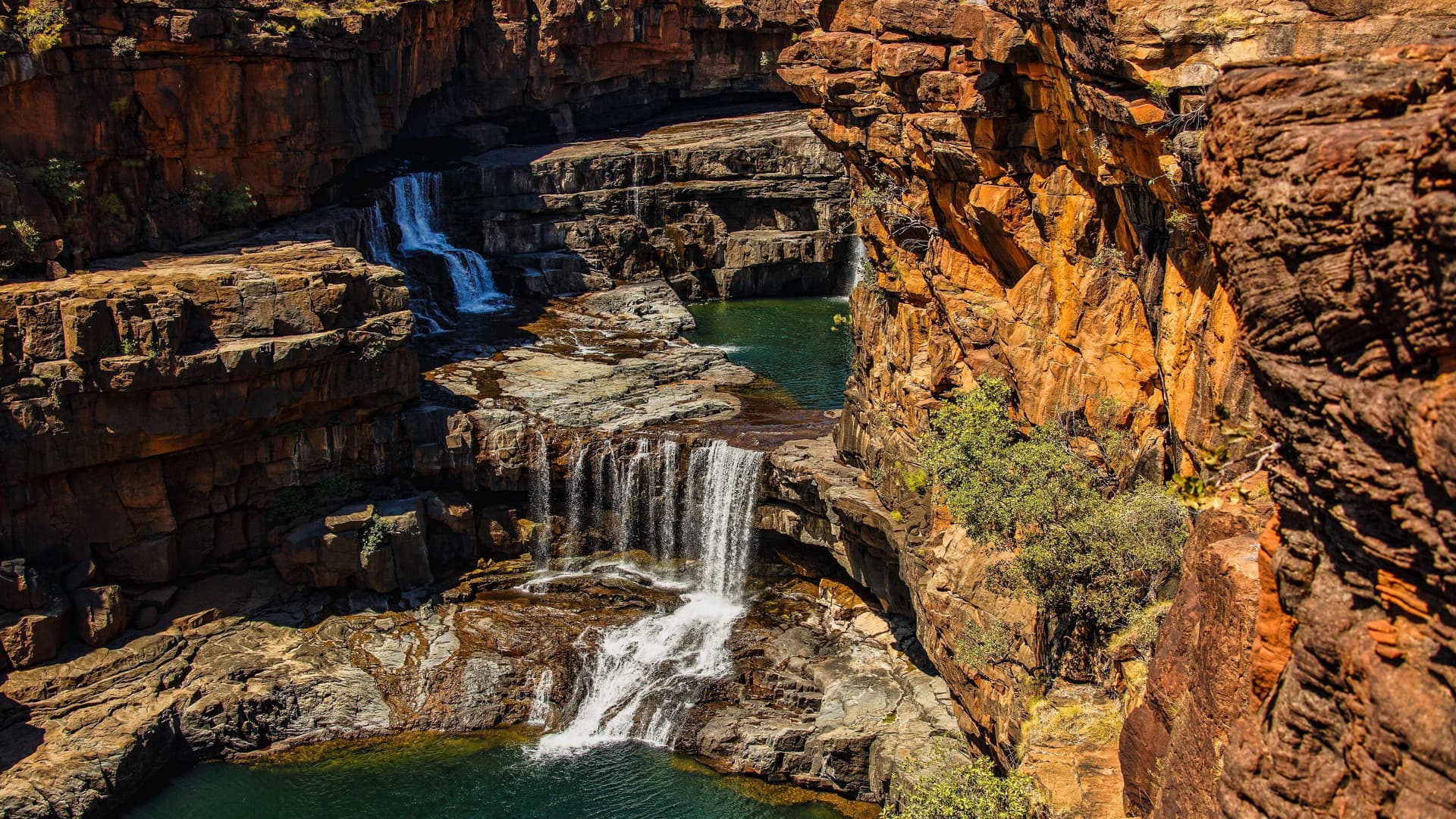 Waterfall and orange-tinted rocks in Kimberley, Australia.