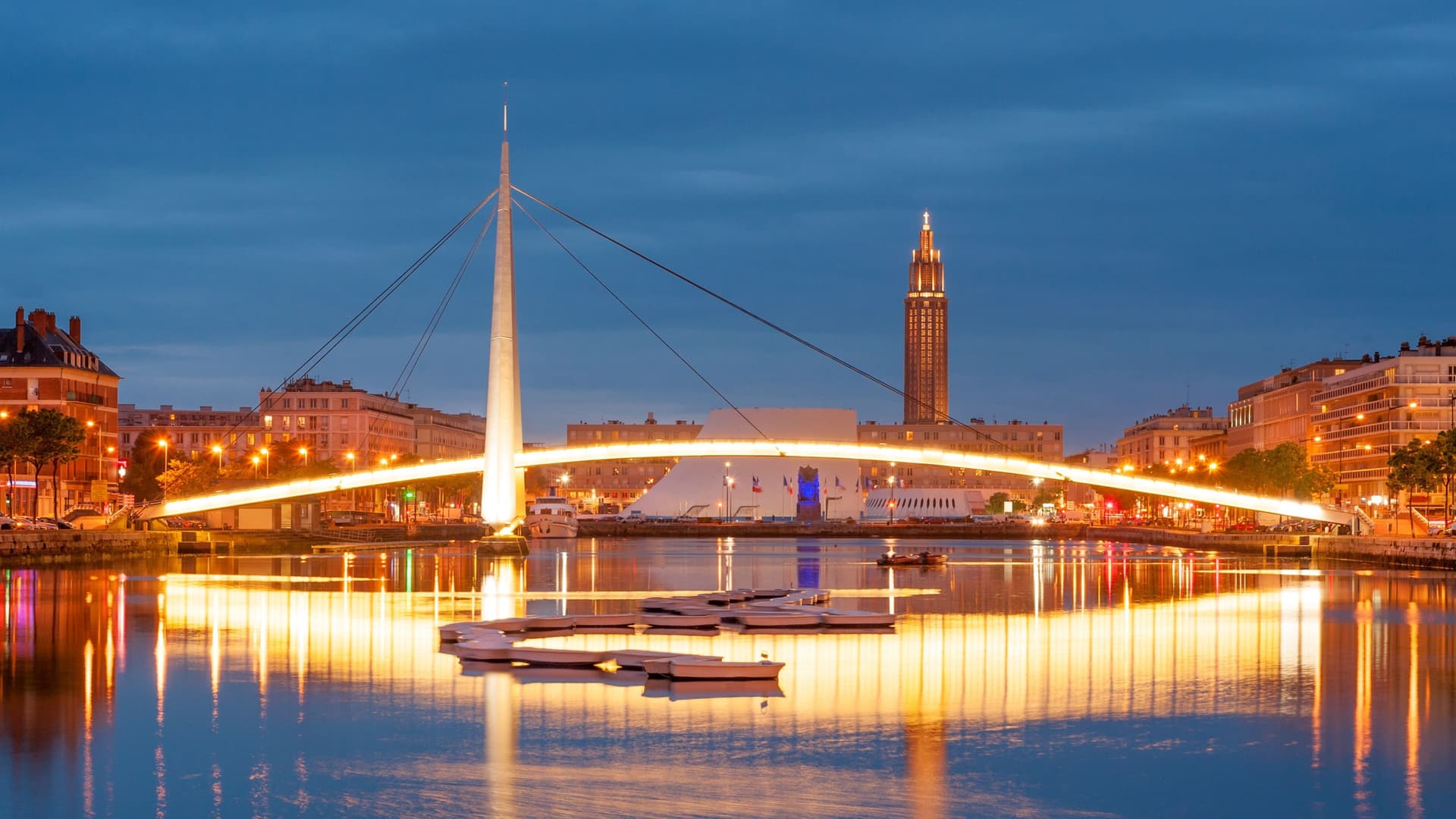 Illuminated bridge and city buildings at dusk in Le Havre, France.