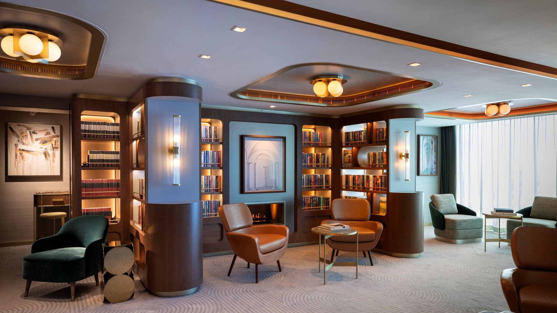 An elegantly designed ship library featuring built-in dark wood bookshelves, comfortable orange leather and green velvet armchairs, warm recessed lighting, and a patterned carpet.