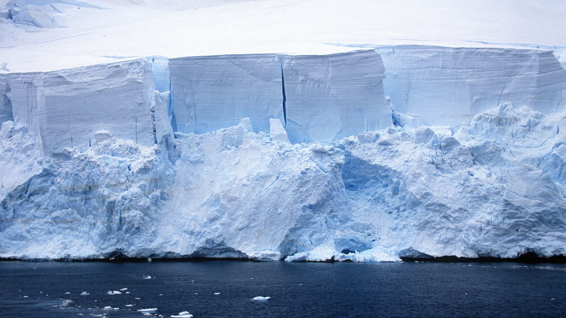 A huge glacier wall with jagged edges and deep cracks, a beautiful landmark in the waters of Paradise Bay, Antarctica.