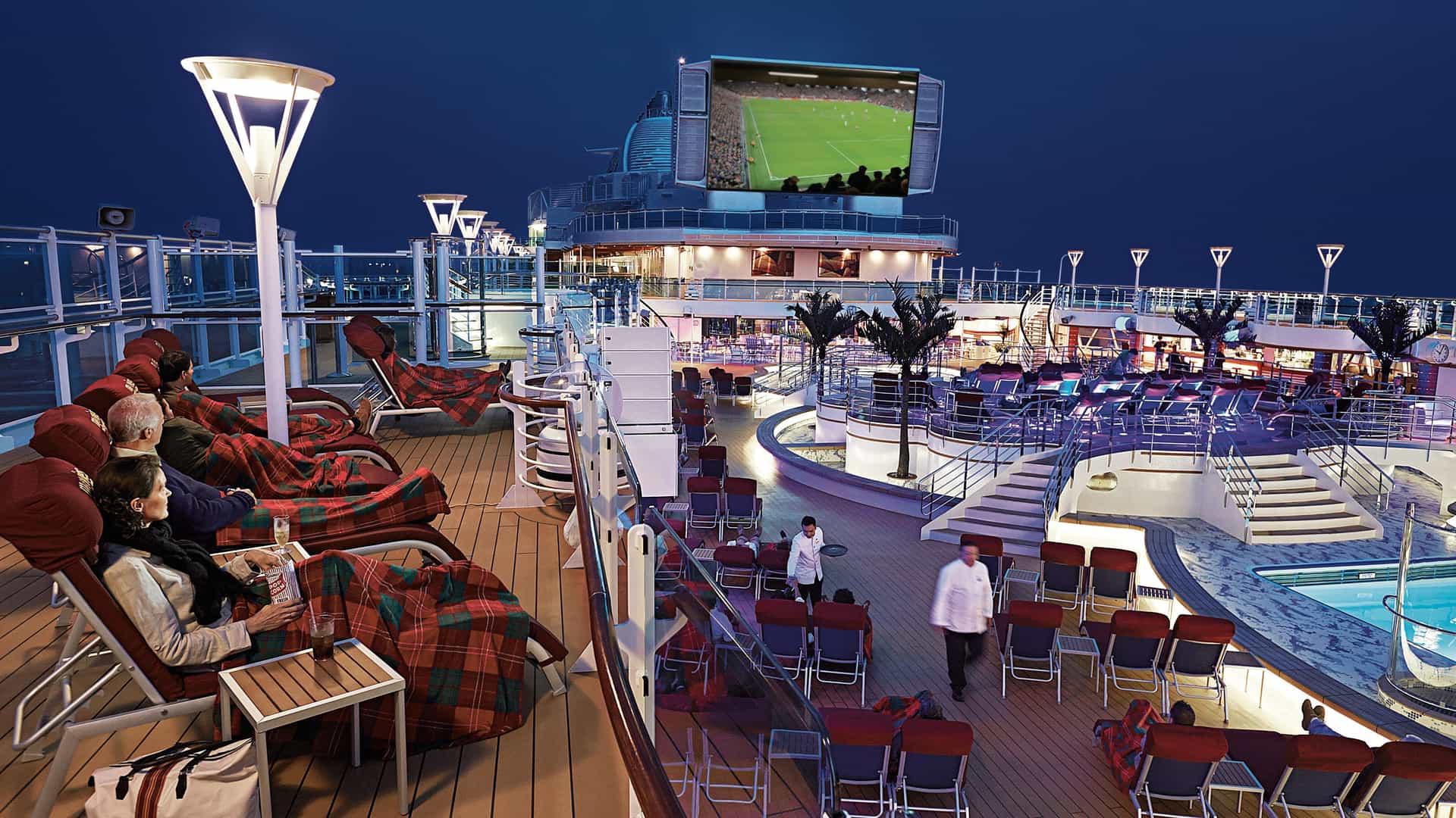 People on Royal Princess' deck watching a soccer match at a Movie Under the Stars event.