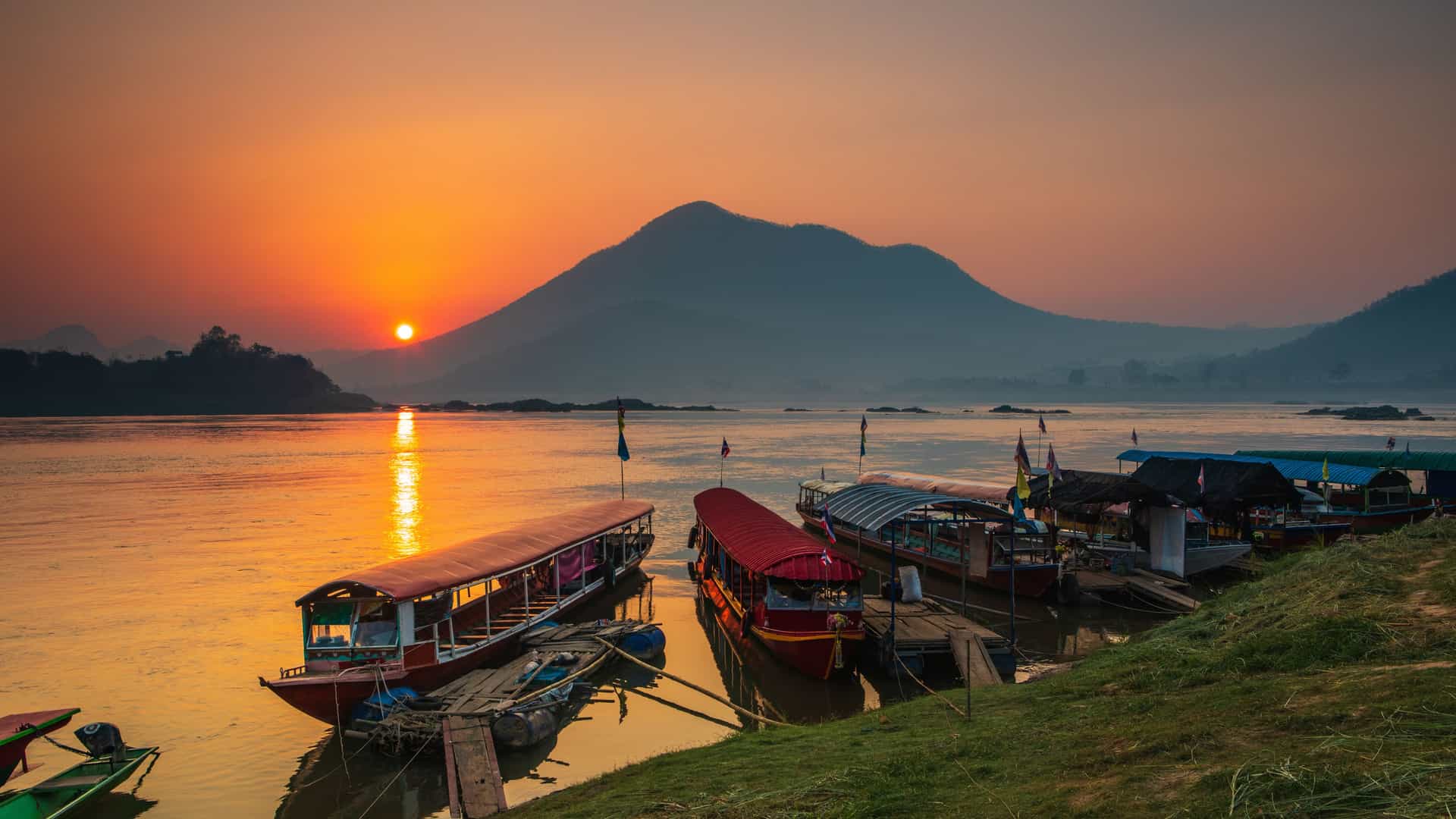 Sunset over an Asian river with traditional boats, reflecting AmaWaterways Mekong River cruise experiences.