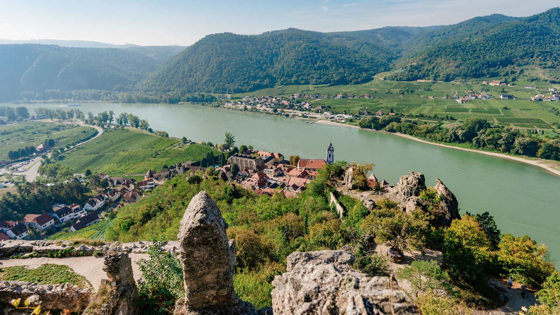 A panoramic view of the historic town of Dürnstein, Austria, and the Kuenringer Castle ruins overlooking the Danube River, a popular stop on an AmaWaterways cruise through the Wachau Valley.