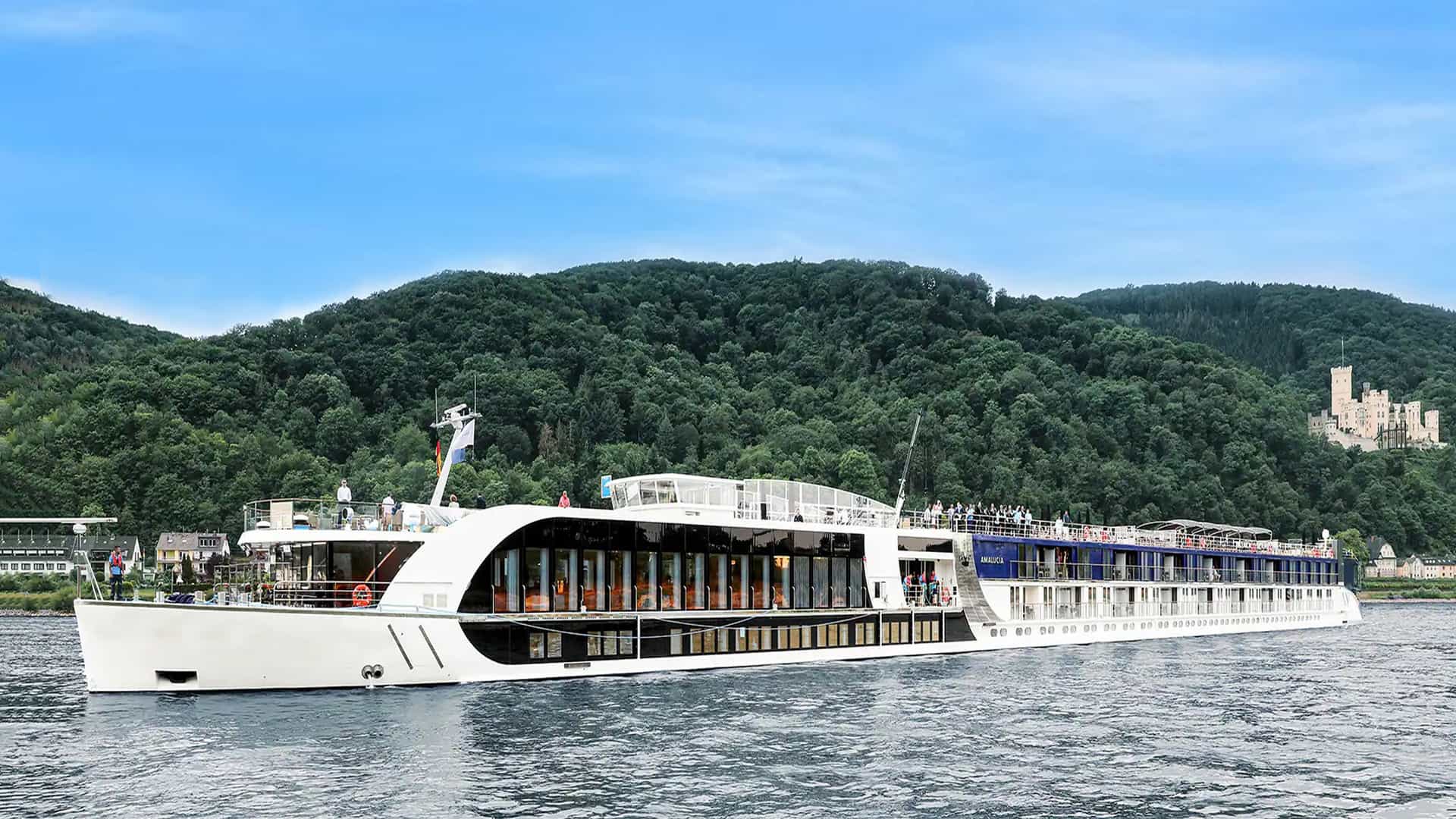Amawaterways AmaFiora river ship sailing withe luscious green trees and hills in the background.