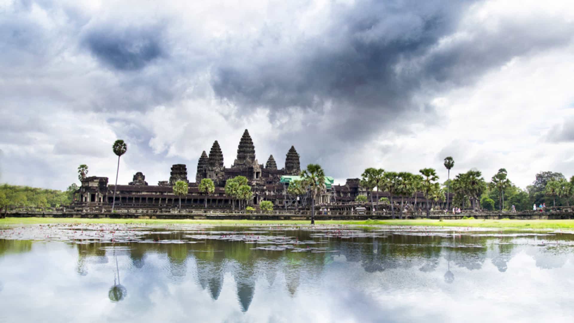Majestic Angkor Wat temple complex in Siem Reap, Cambodia, reflected in calm waters under a dramatic sky, a highlight of Avalon Waterways Mekong River cruises.