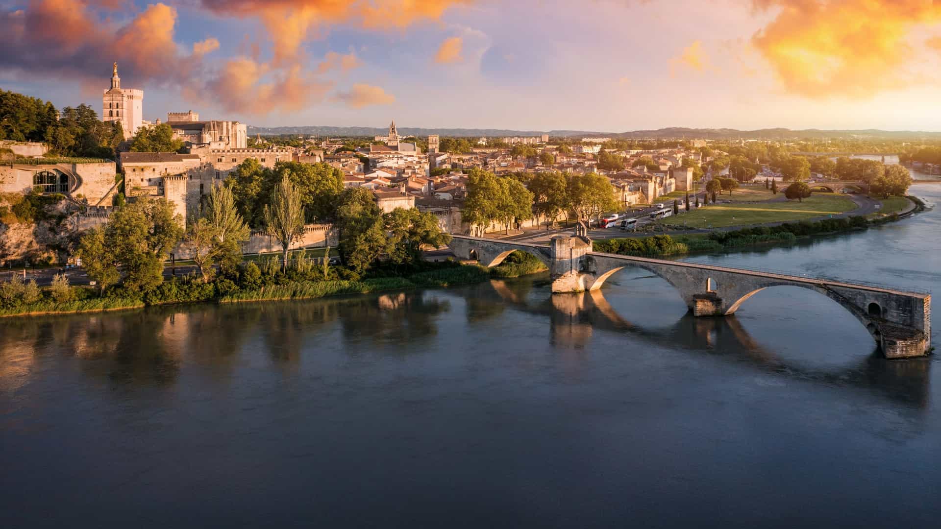 Historic Avignon, France, featuring the iconic Pont Saint-Bénézet and the medieval Papal Palace, set along the Rhône River under a beautiful sunset, a picturesque stop on an Avalon Waterways cruise.