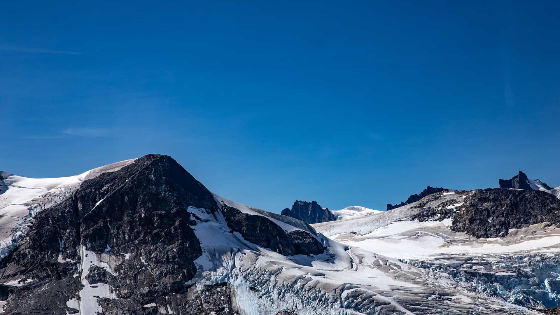 Panoramic view of snow-capped mountains and a glacier in Alaska, likely seen during an Azamara Cruises shore excursion from Skagway.