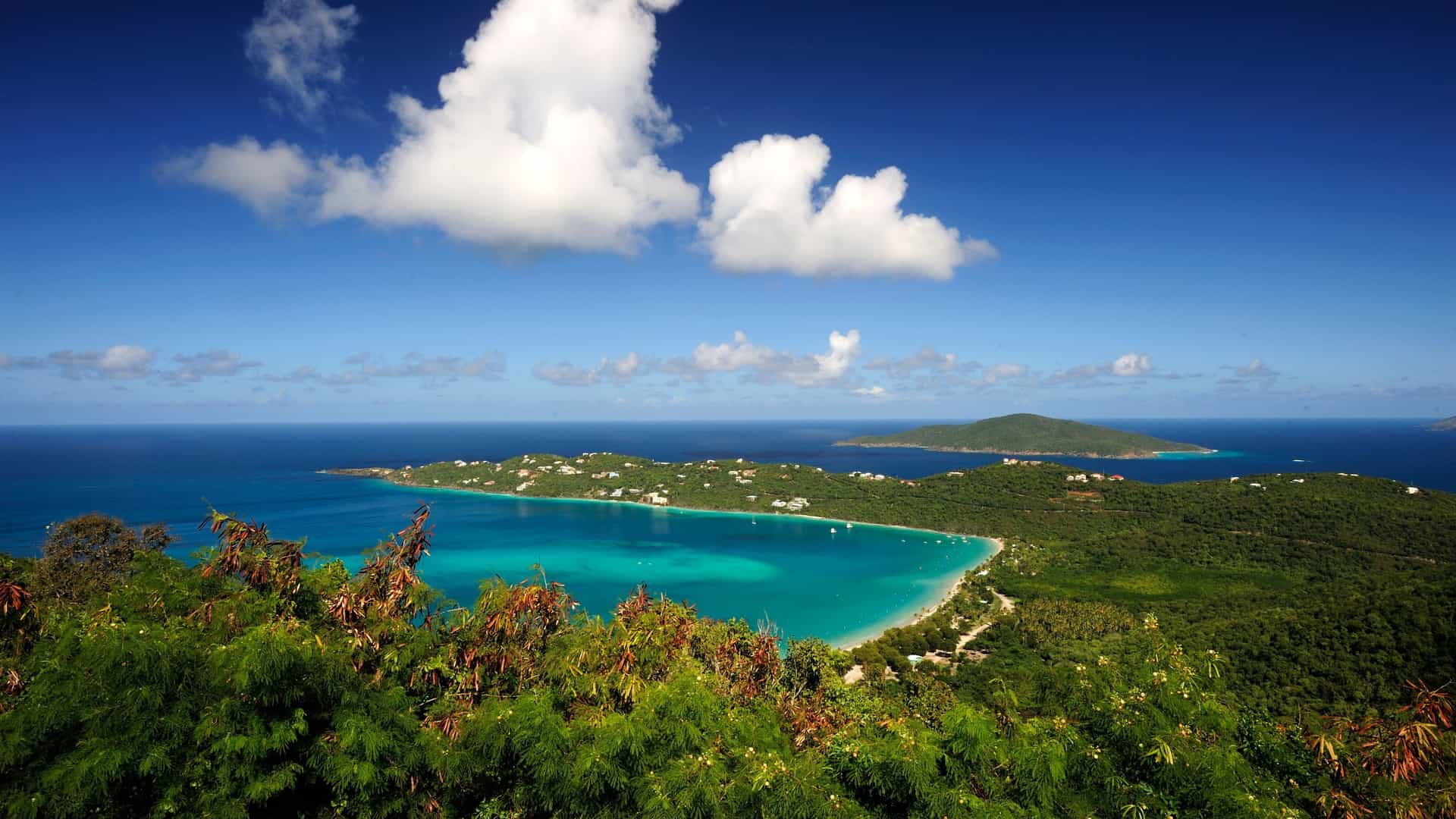 Panoramic view of Magens Bay in St. Thomas, Eastern Caribbean, with its turquoise waters and lush green hills under a bright blue sky, a popular stop for Carnival cruises.