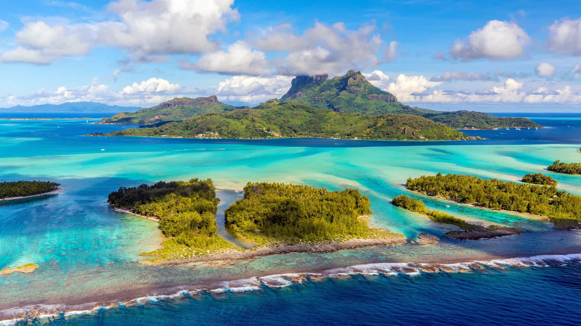 Panoramic view of Bora Bora with green mountains, turquoise lagoons, and motus on a Celebrity Cruises South Pacific itinerary.