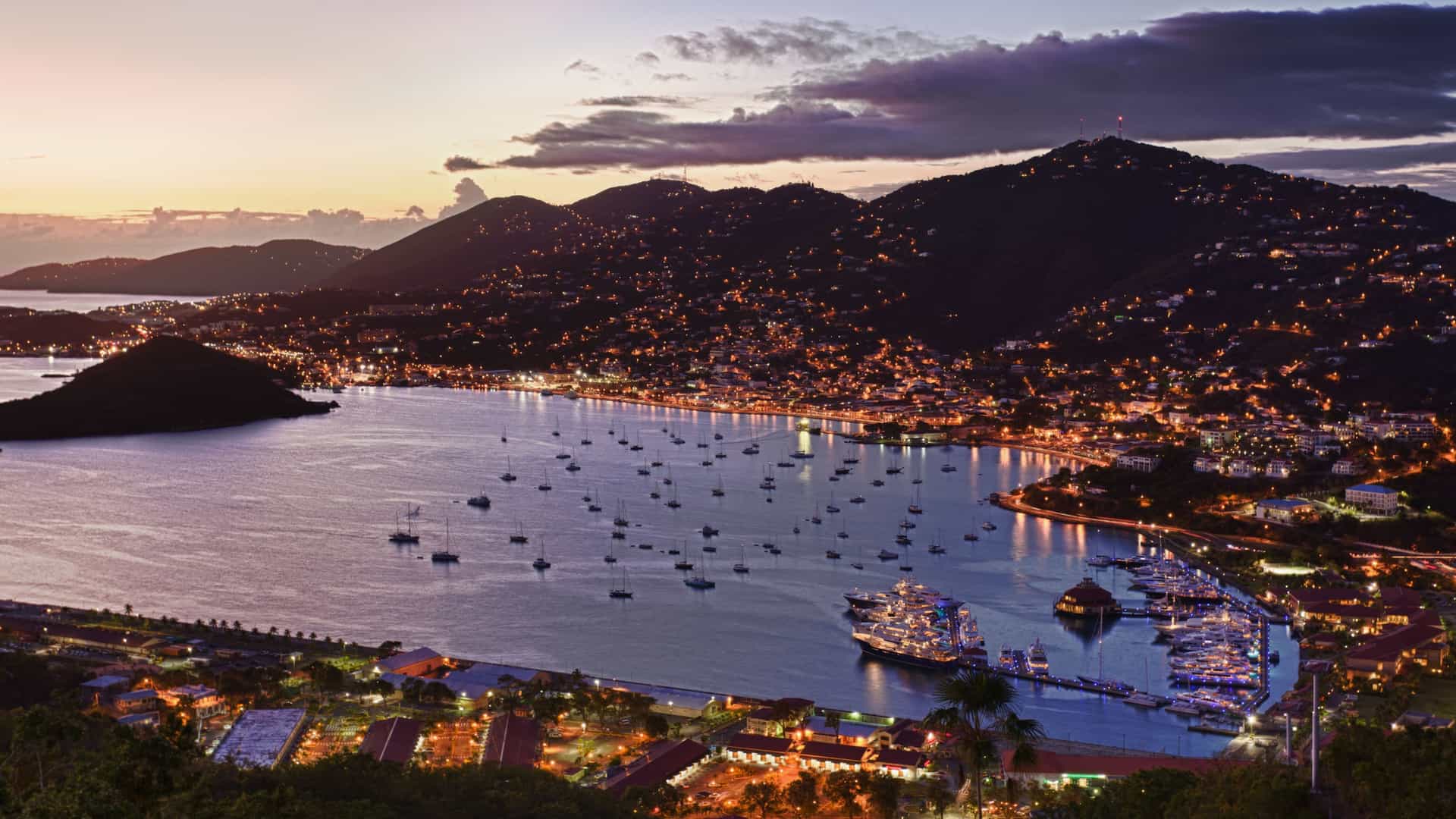 A wide shot encompassing all of Charlotte Amalie, St. Thomas, show casing the tropical city's lights during sunset.