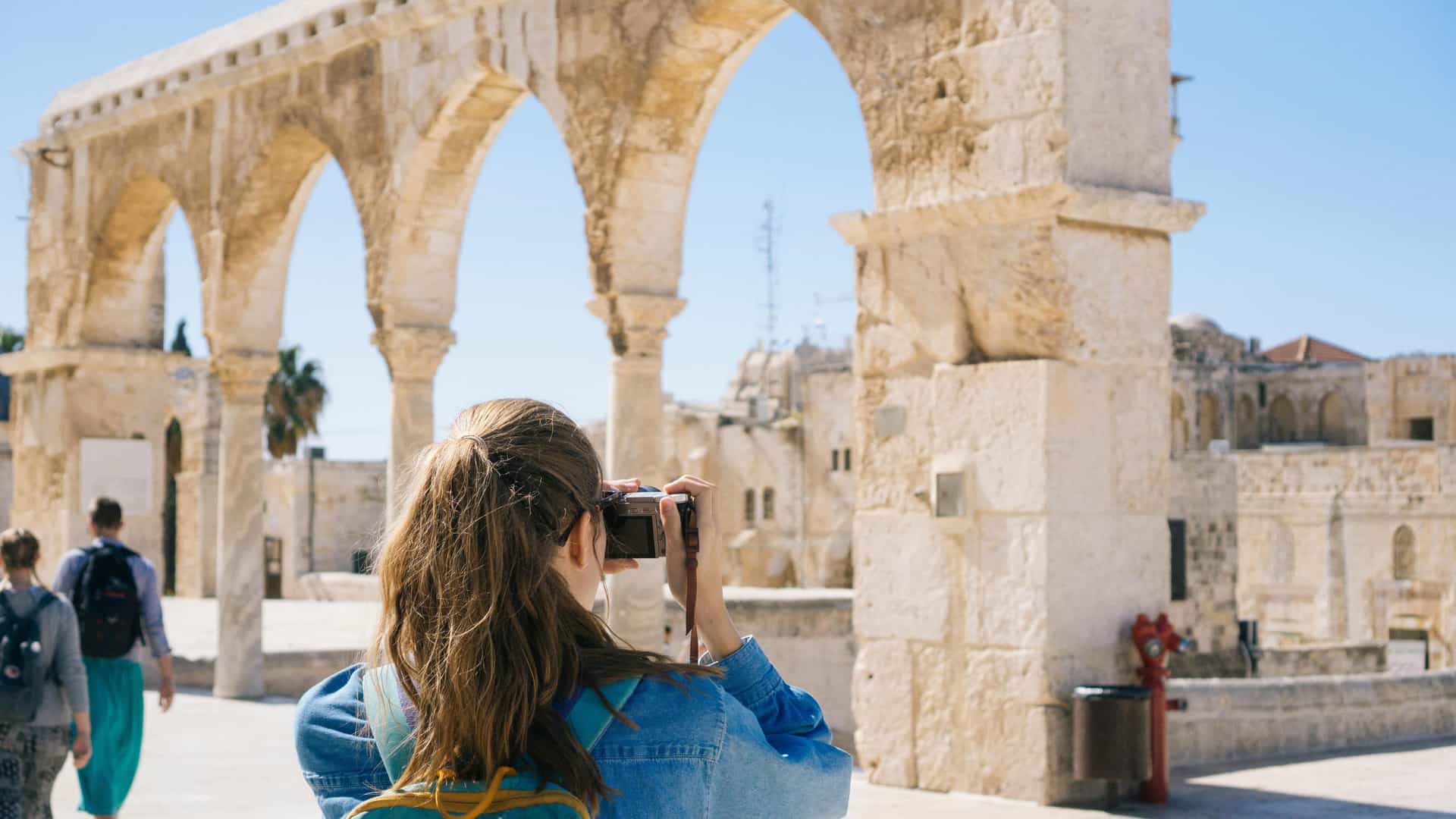 A solo female traveler taking photos of ancient ruins while on a Cosmos tour.