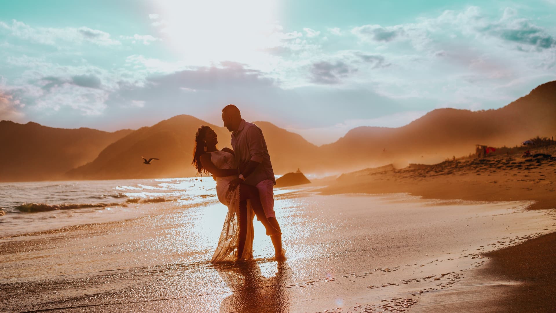 A smiling couple dancing on the beach on a warm summer day.