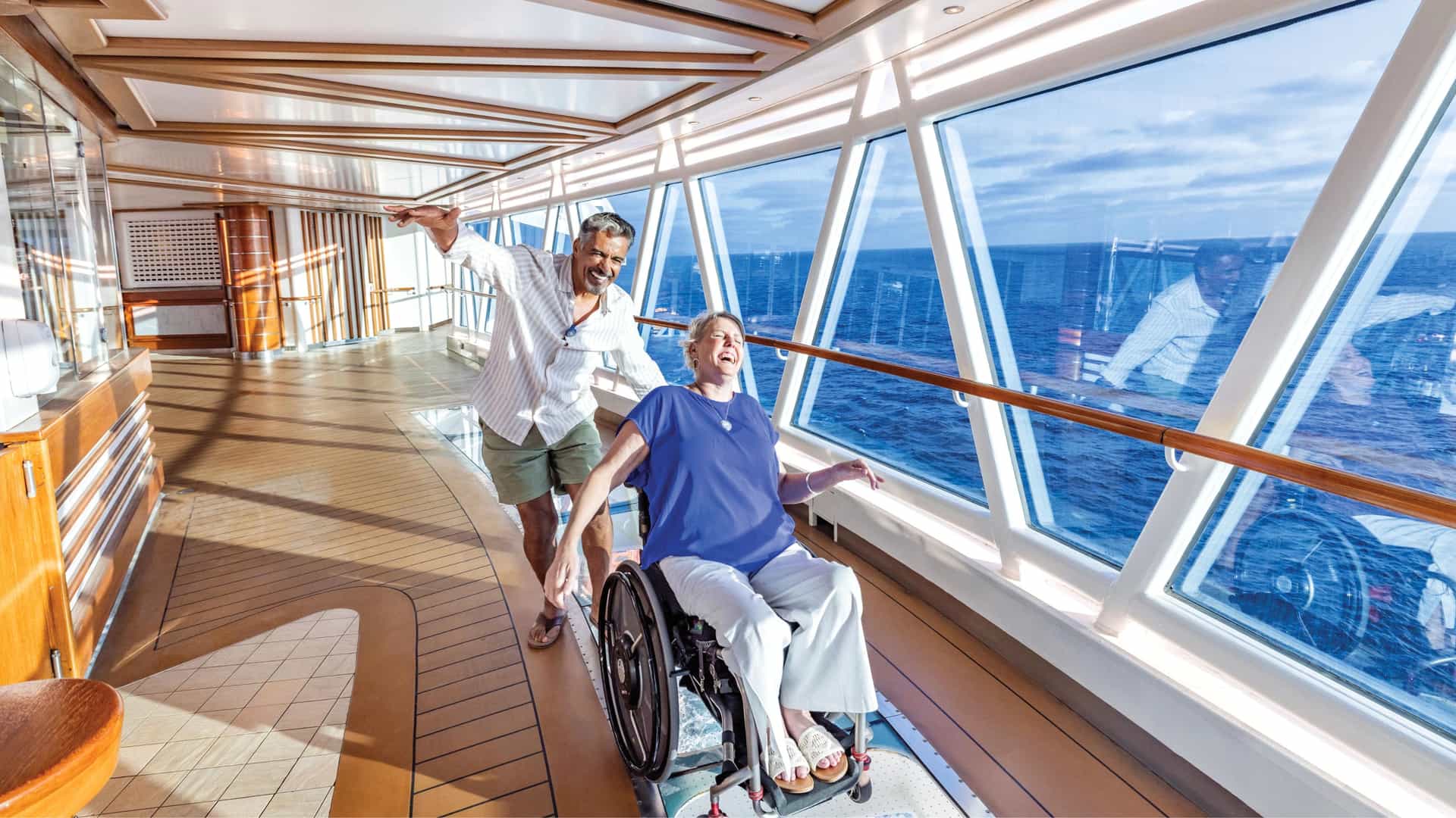 Man and woman in a wheelchair laughing in the Skywalk on a Princess Cruise ship.
