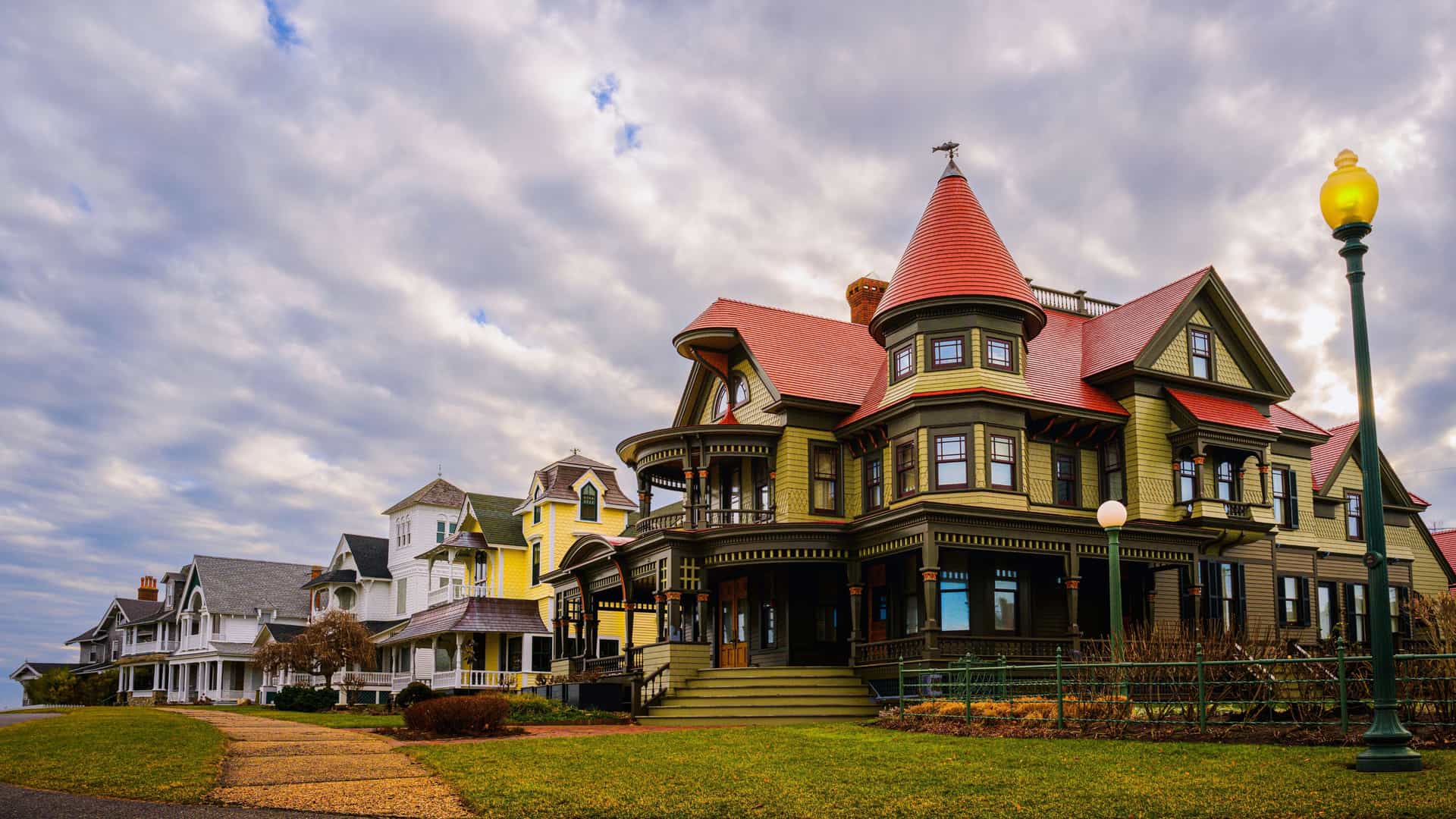 Colorful Victorian gingerbread cottages in Oak Bluffs on Martha’s Vineyard, Massachusetts, with ornate trim and gabled roofs lining a curved coastal street under a bright sky.