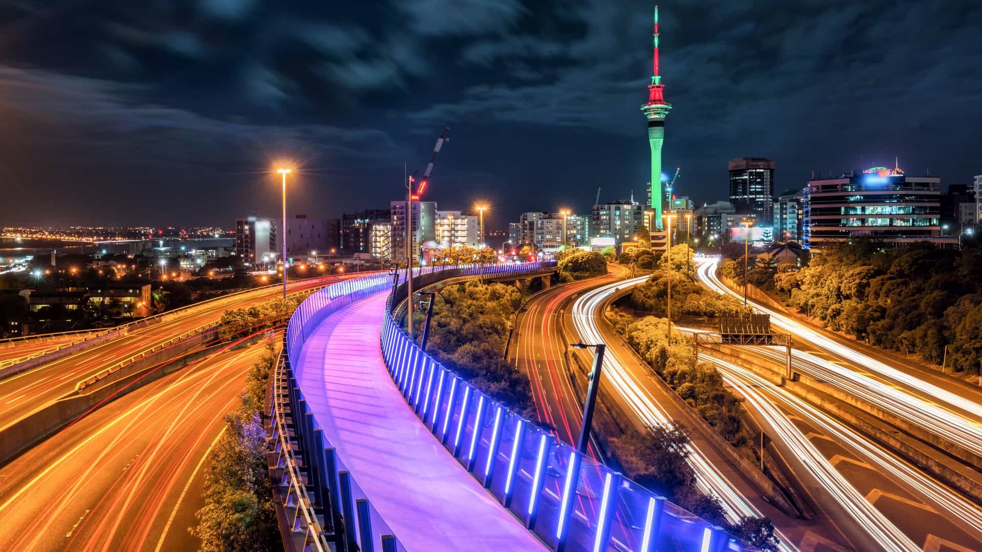The Auckland Sky Tower, an iconic landmark in New Zealand, is illuminated against a dark night sky. The tall, slender structure stands out in the city's skyline, with its unique design and bright lights making it a central focal point of the cityscape. The image highlights the tower's architectural details and its function as a prominent nighttime feature of Auckland.