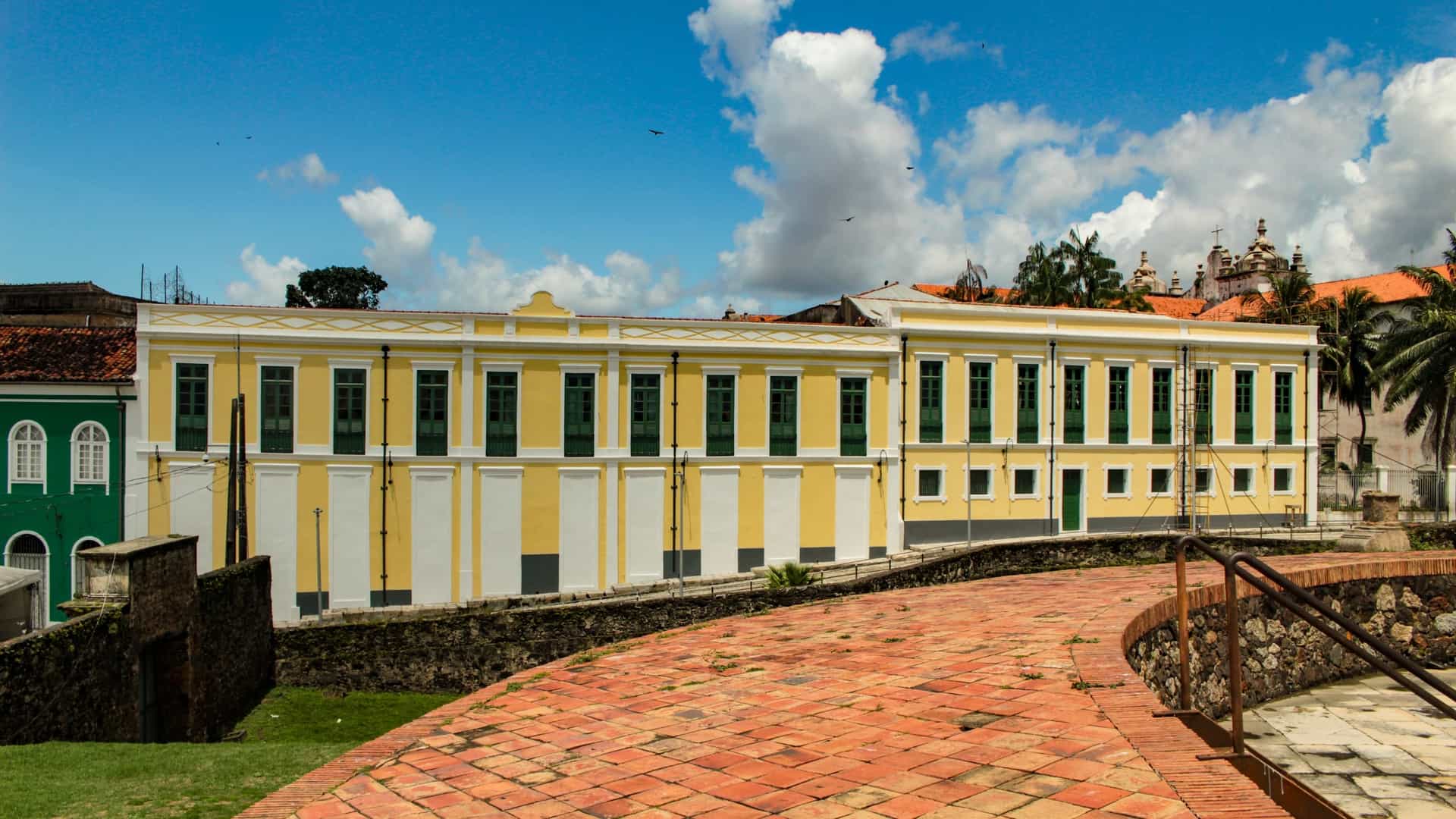 A close up view of the historic Portuguese colonial style building facades in the Feliz Lusitânia complex in Belém, Pará, Brazil. The multi story structures are painted in vibrant colors, featuring detailed architectural elements such as ornate iron balconies and ceramic tiles, characteristic of the city's rich Amazonian architecture from the late 19th and early 20th centuries.