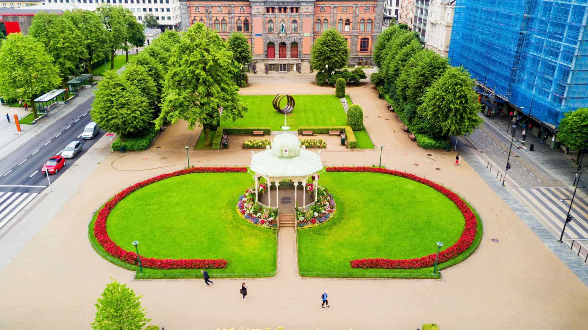 The imposing Neo Renaissance facade of the KODE 1 (Permanenten) art museum in Bergen, Norway. The grand stone building, which houses collections of decorative art and design, stands behind the elaborate, light colored, Moorish style Musikkpaviljongen (Music Pavilion) in Byparken (City Park), with the pavilion's domed roof framed against the museum's upper stories.