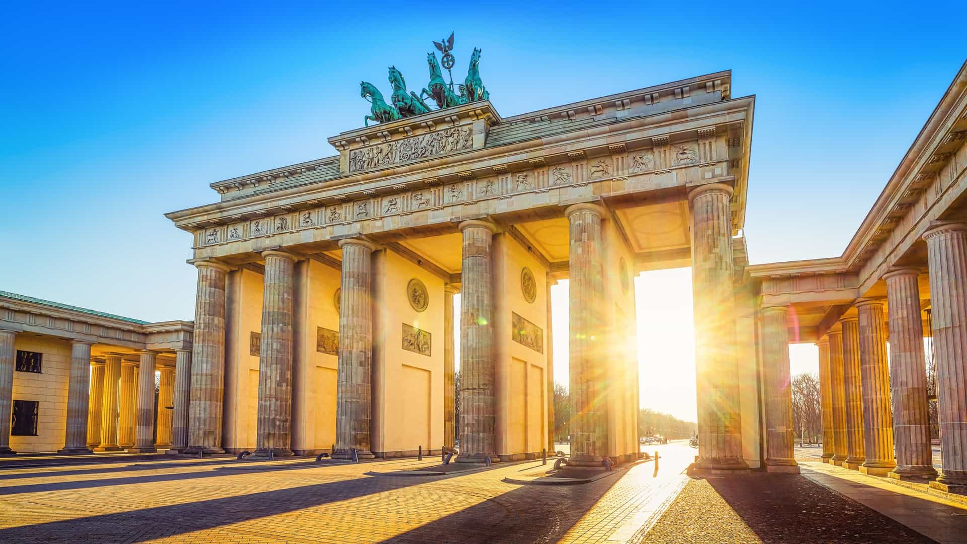 The iconic Brandenburg Gate (Brandenburger Tor) in Berlin, Germany, captured at sunset with the Quadriga statue visible atop the neoclassical archway.
