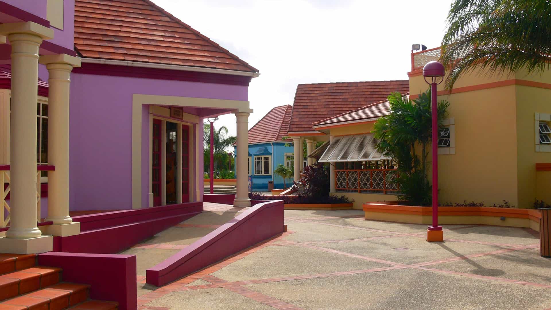 The colorful buildings and sign for the Pelican Craft Village in Barbados, showcasing the marketplace for local arts, crafts, and culture.