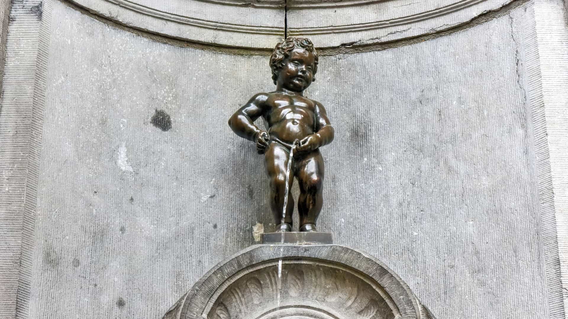 A close up, straight on shot of the famous bronze fountain statue, Manneken Pis ("Little Pissing Man"), in Brussels, Belgium, showing the nude boy figure standing and urinating into the basin.