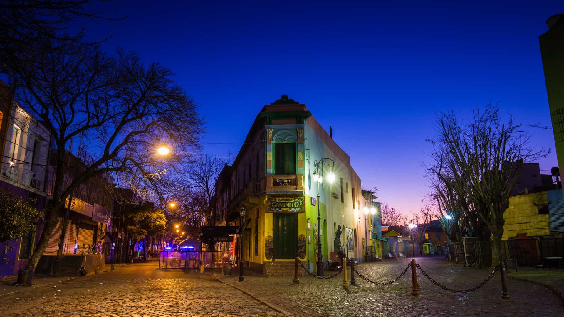 The colorful, vibrant houses and shops of Caminito in the La Boca neighborhood of Buenos Aires, Argentina, featuring corrugated metal walls and art installations in the pedestrian street.