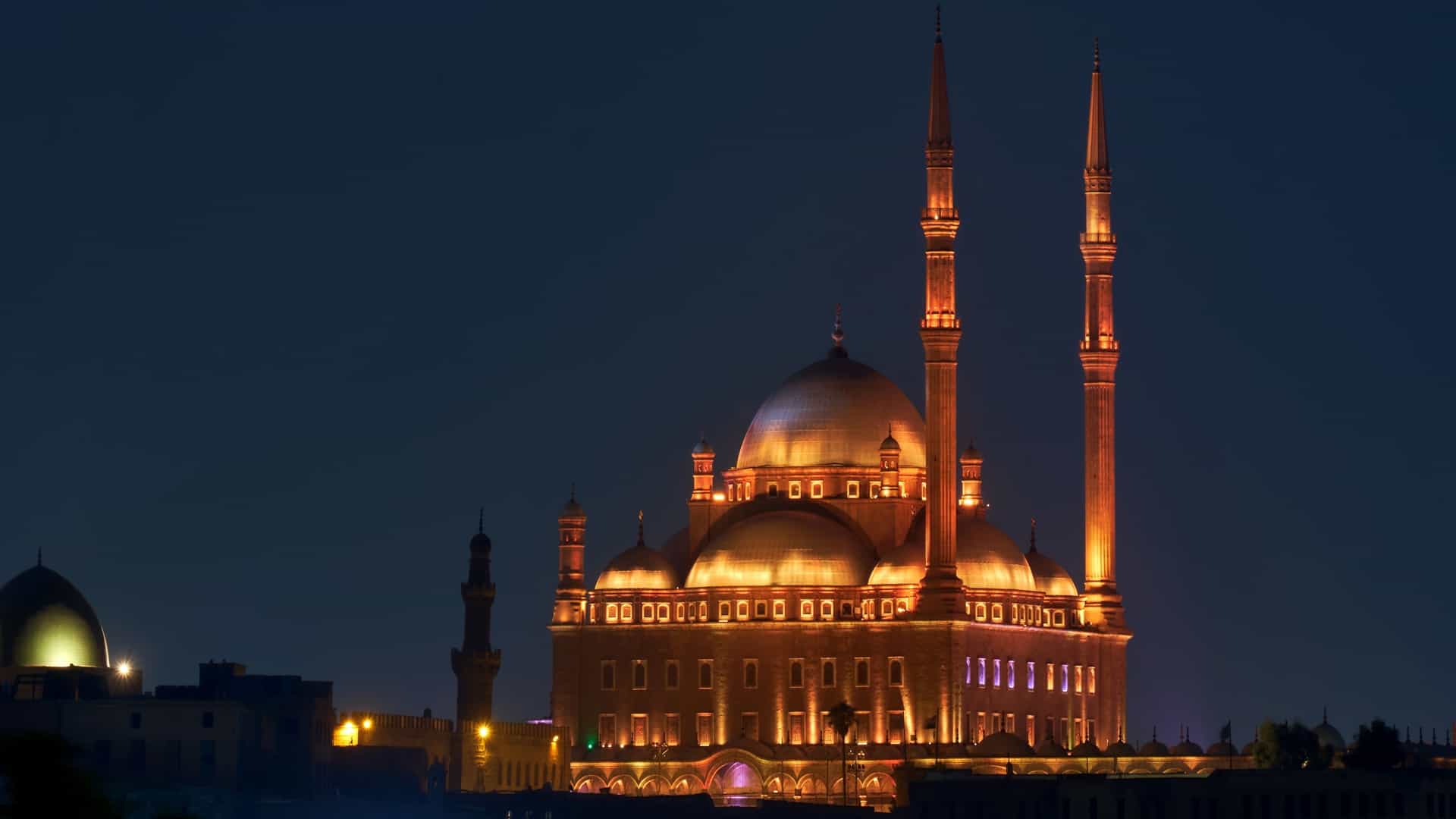 A panoramic view of the Saladin Citadel of Cairo in Egypt, as seen from the elevated vantage point of Al-Azhar Park, with the surrounding city extending into the distance.