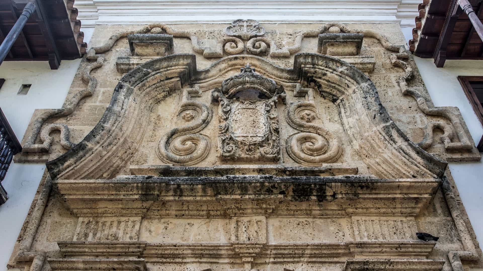 The elaborate Baroque style facade of the Palace of the Inquisition in Cartagena de Indias, Colombia, is highlighted in this photo. This Spanish colonial architectural masterpiece, which currently serves as a historical museum, is framed by its ornate stone entrance and iconic wooden balconies.
