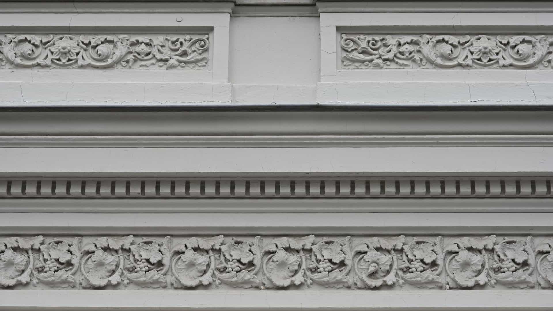 A detailed close-up of a decorative facade and cornice on a building constructed in the Art Nouveau style, featuring ornate, sculpted floral and organic motifs.