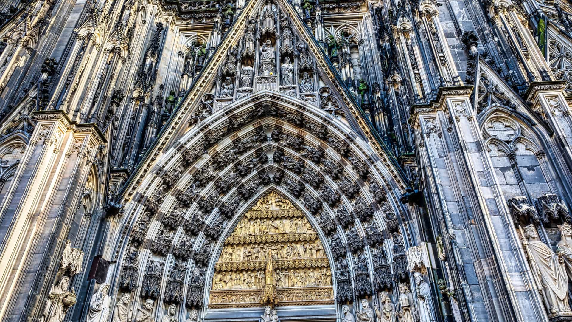 A majestic exterior view of the Cologne Cathedral (Kölner Dom) in Cologne, Germany, a renowned masterpiece of Gothic architecture, showcasing its soaring twin spires and intricately carved stone facade.