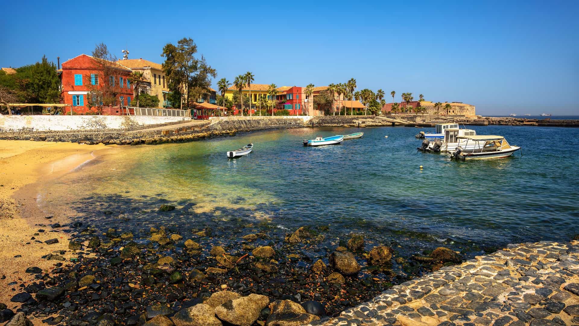 A historic city on Gorée Island, a UNESCO World Heritage Site off the coast of Dakar, Senegal. The image shows a view of the colorful colonial era buildings and the bay, reflecting the island's historical significance as a former center of the transatlantic slave trade.