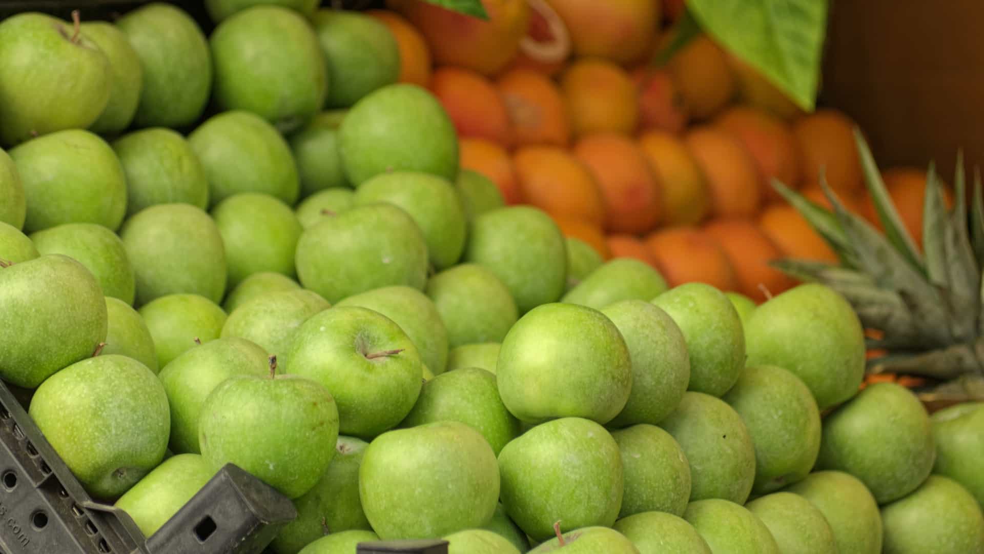 A large, colorful mound of fresh, bright green apples for sale. The photo captures a typical market stall produce display near the retail area of Smith Street Mall, Darwin.