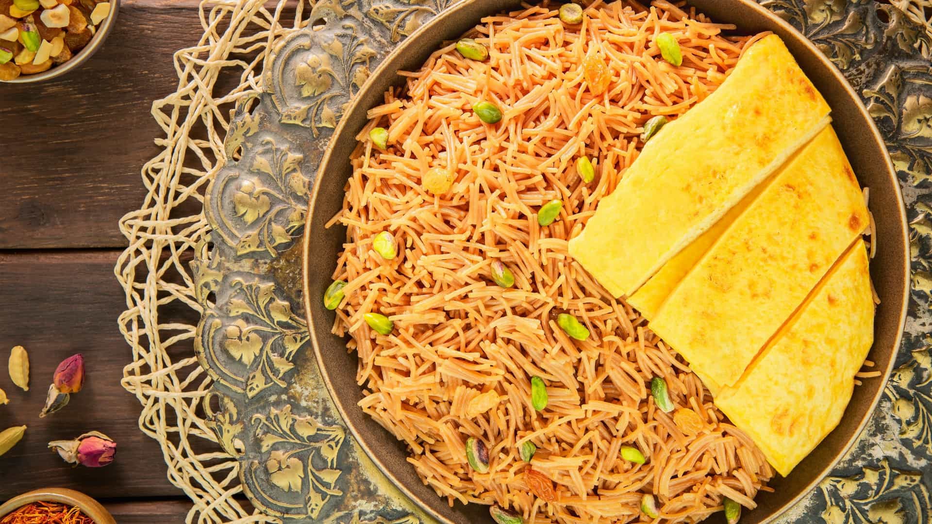 Close up, top down view of Balaleet, a traditional Middle Eastern sweet and savory dish. The base consists of thin, saffron colored vermicelli noodles seasoned with cardamom and other spices, topped with a thin, folded egg omelet.