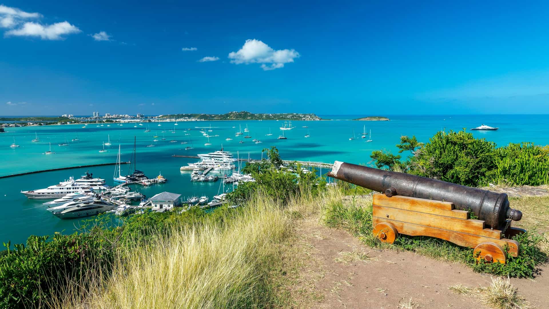 A panoramic view of the fortified Fort Louis overlooking the calm, turquoise waters of the bay in Marigot, the capital of Saint Martin, a French Caribbean island.
