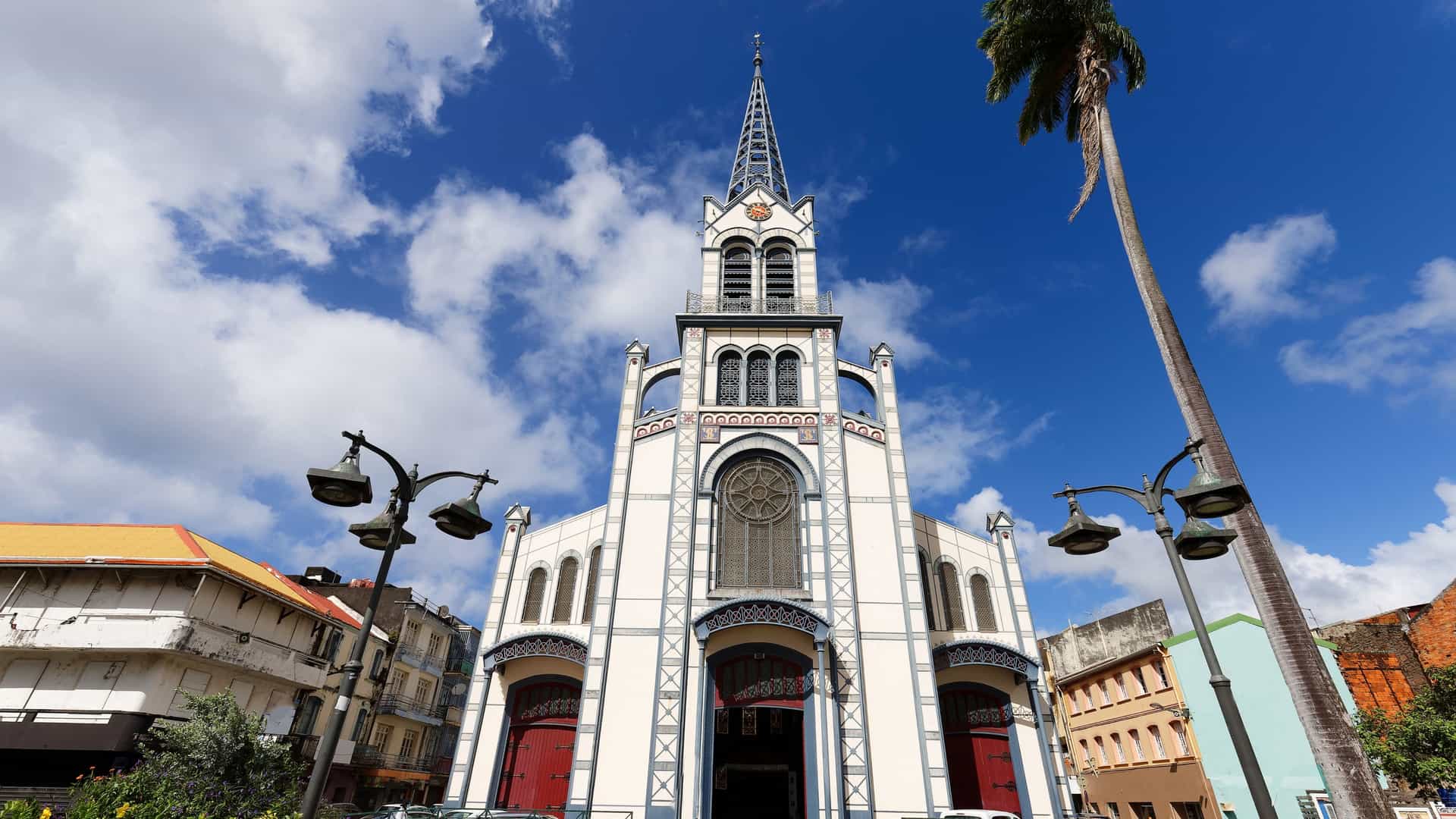 The tall, spire-topped bell tower of the St. Louis Cathedral dominates the sky in Fort-de-France, Martinique. The church displays a unique combination of iron-framework construction and Romanesque Revival style, designed to withstand earthquakes.