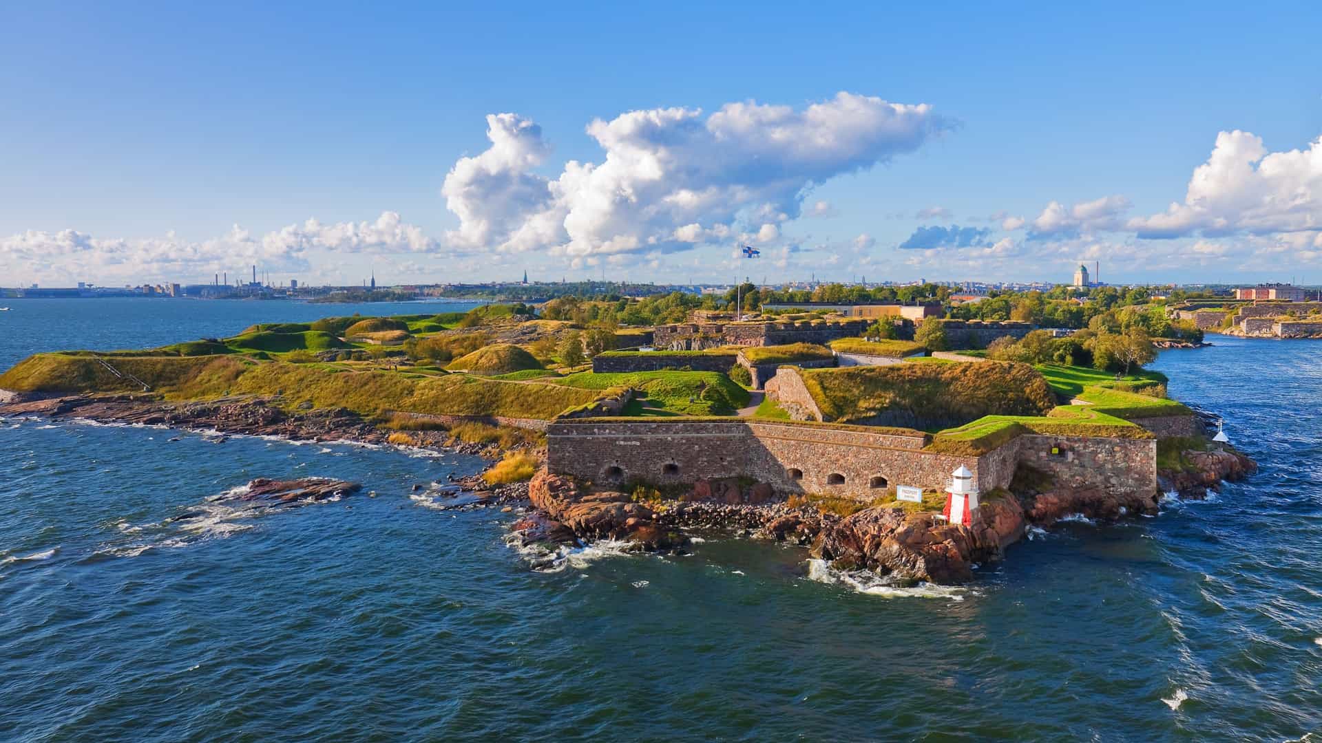 A photograph of the Suomenlinna sea fortress in Helsinki, Finland. The image captures the historic fortifications, including stone walls and defensive structures, as they sit on a rocky shoreline. In the foreground, the sea is visible, and the fortress buildings are set against the backdrop of the sky.