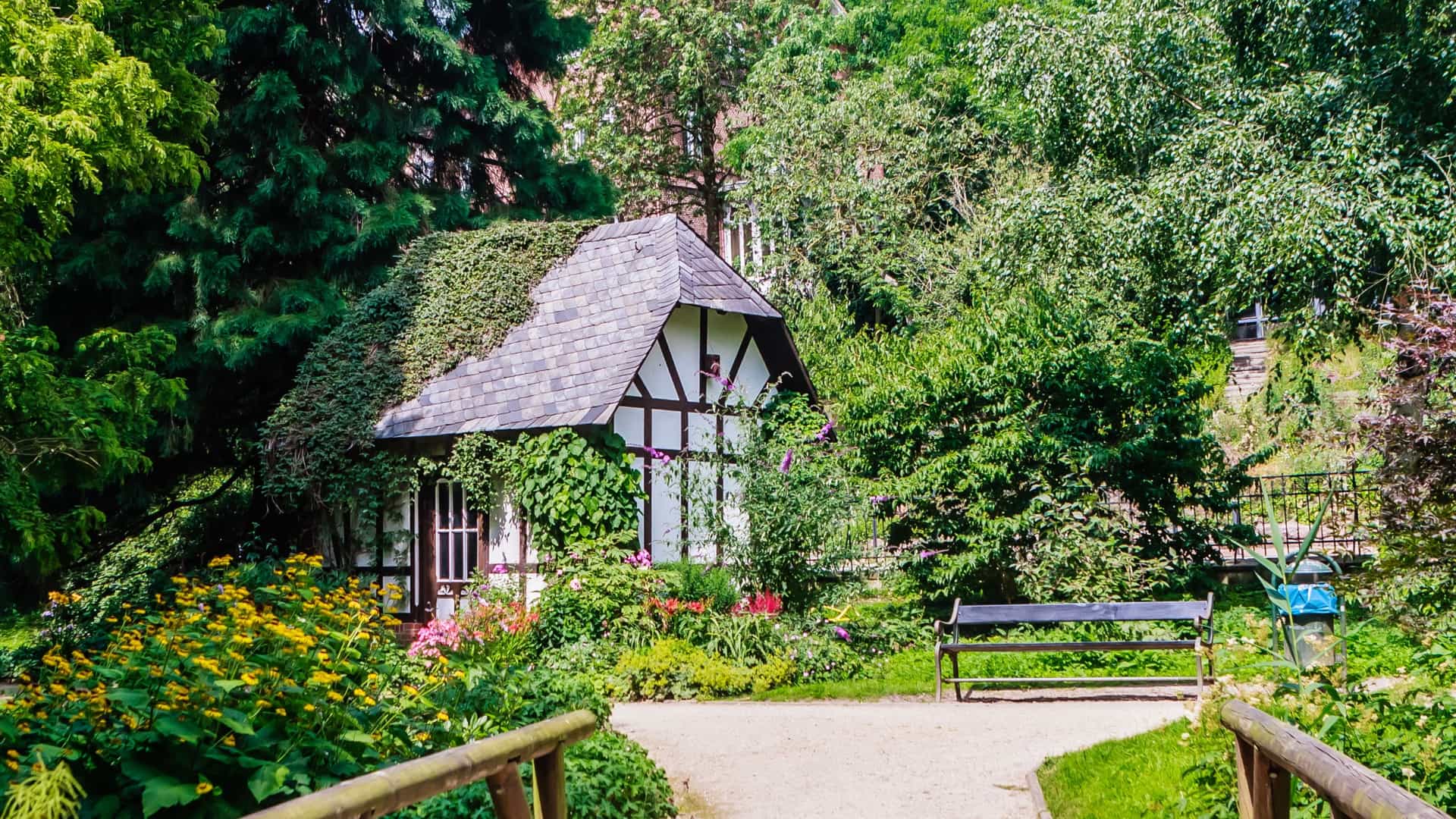A view of the Literaturhaus Schleswig-Holstein (Literature House) in Kiel, Germany. The building is a historic, half-timbered house (a Fachwerkhaus) that was formerly the garden inspector's cottage, situated within the Old Botanical Garden. The two-story structure features dark timber framing against light-colored walls, a pitched roof, and is surrounded by the lush trees and greenery of the historic park.