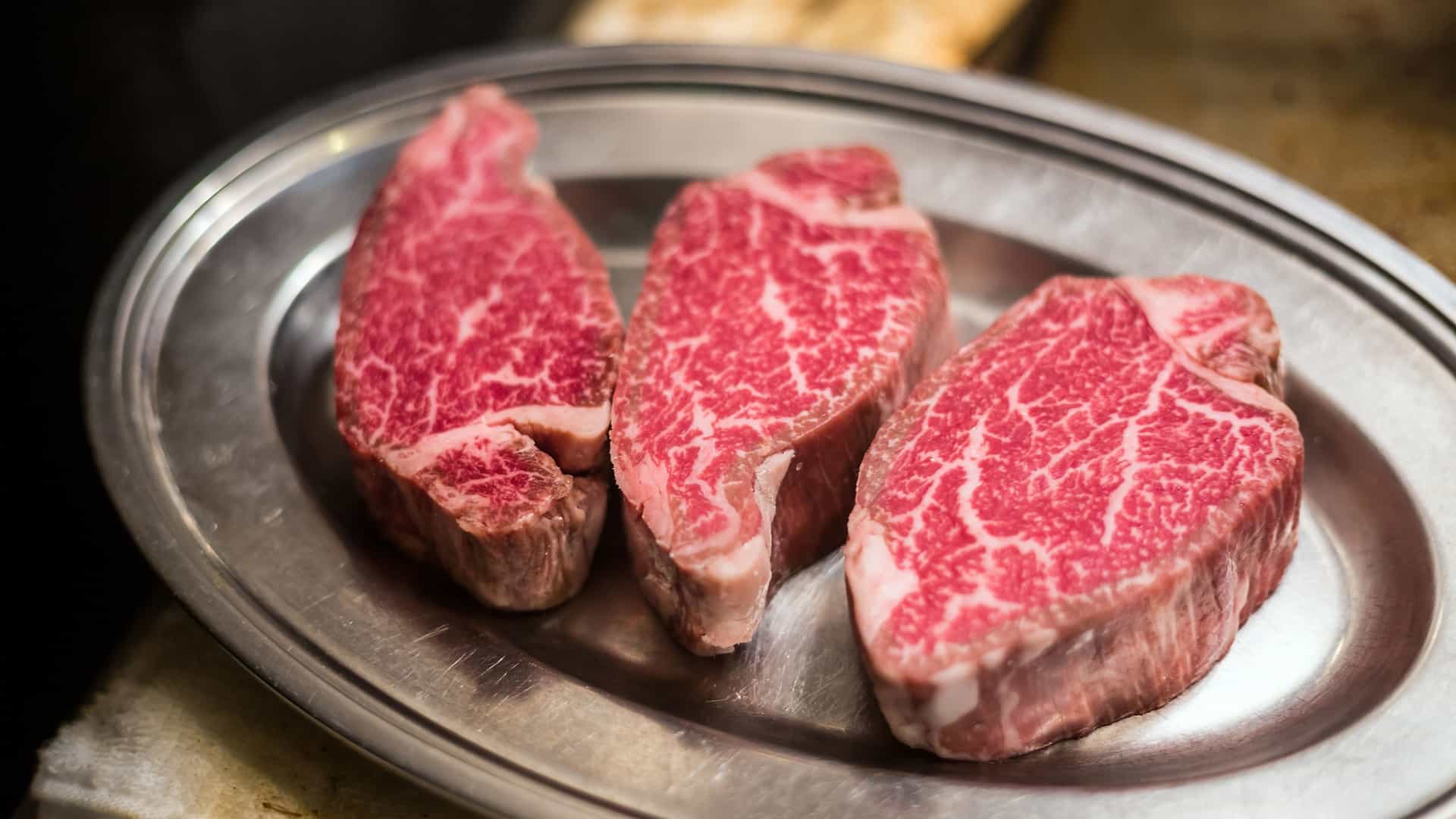 A close up shot of a raw, premium Kobe beef steak from Japan, showcasing the intricate and beautiful marbling of the meat.