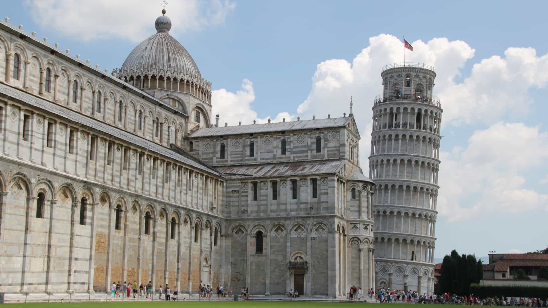 The iconic Leaning Tower of Pisa stands in Pisa, Italy, showcasing its famous tilt and the white marble construction against a clear blue sky.