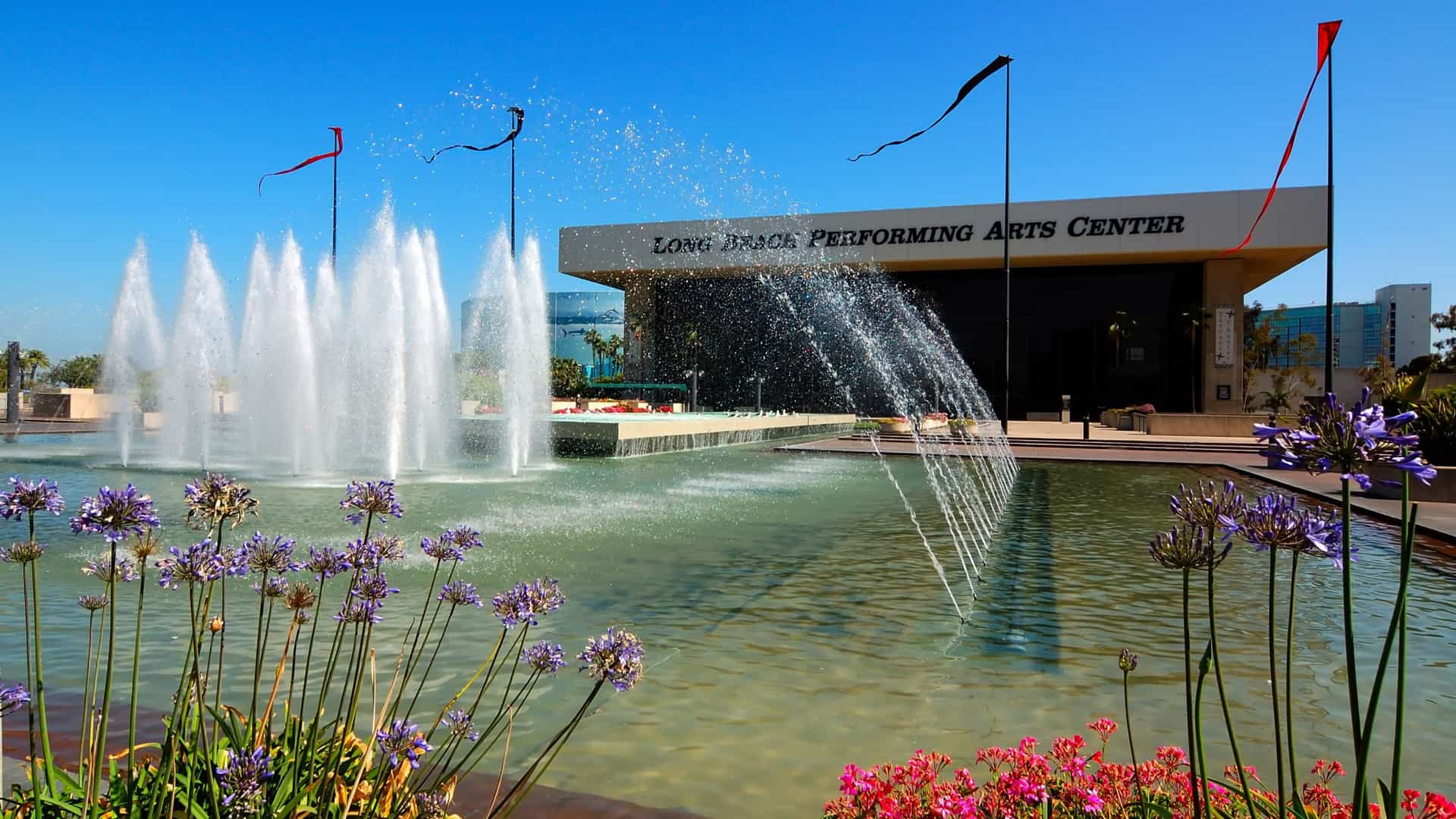 The exterior of the Terrace Theater in Long Beach, California, which houses the International City Theatre located in the Long Beach Performing Arts Center. The building is a prominent part of the Convention Center complex, featuring modernist, circular architecture and a large glass facade, framed by its surrounding water features and plaza.