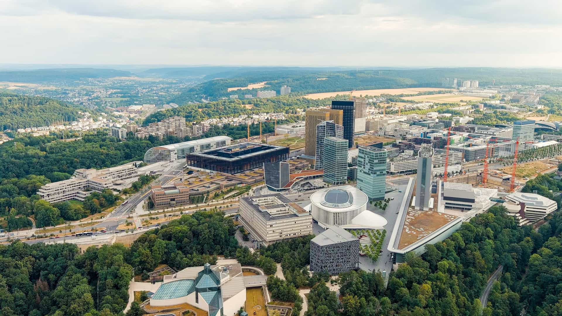 An aerial view of the modern Kirchberg district of Luxembourg City . The image features contemporary high-rise office buildings, residential structures, and the distinct architecture of the area, all set on the plateau that serves as the city's financial and European quarter.