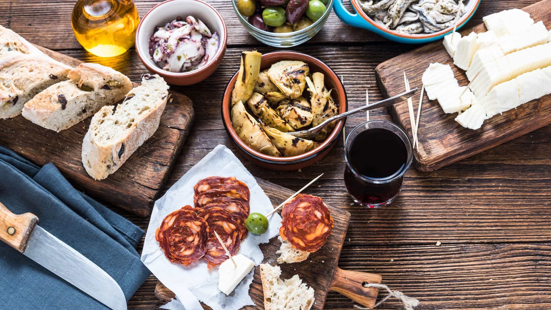 A close up, overhead shot of a group of friends gathered around a table in a restaurant, sharing plates of authentic Spanish tapas. The table is filled with various dishes, including patatas bravas (fried potatoes with sauce), croquetas (fried fritters), and other small plates, highlighting the communal and social aspect of tapas culture.