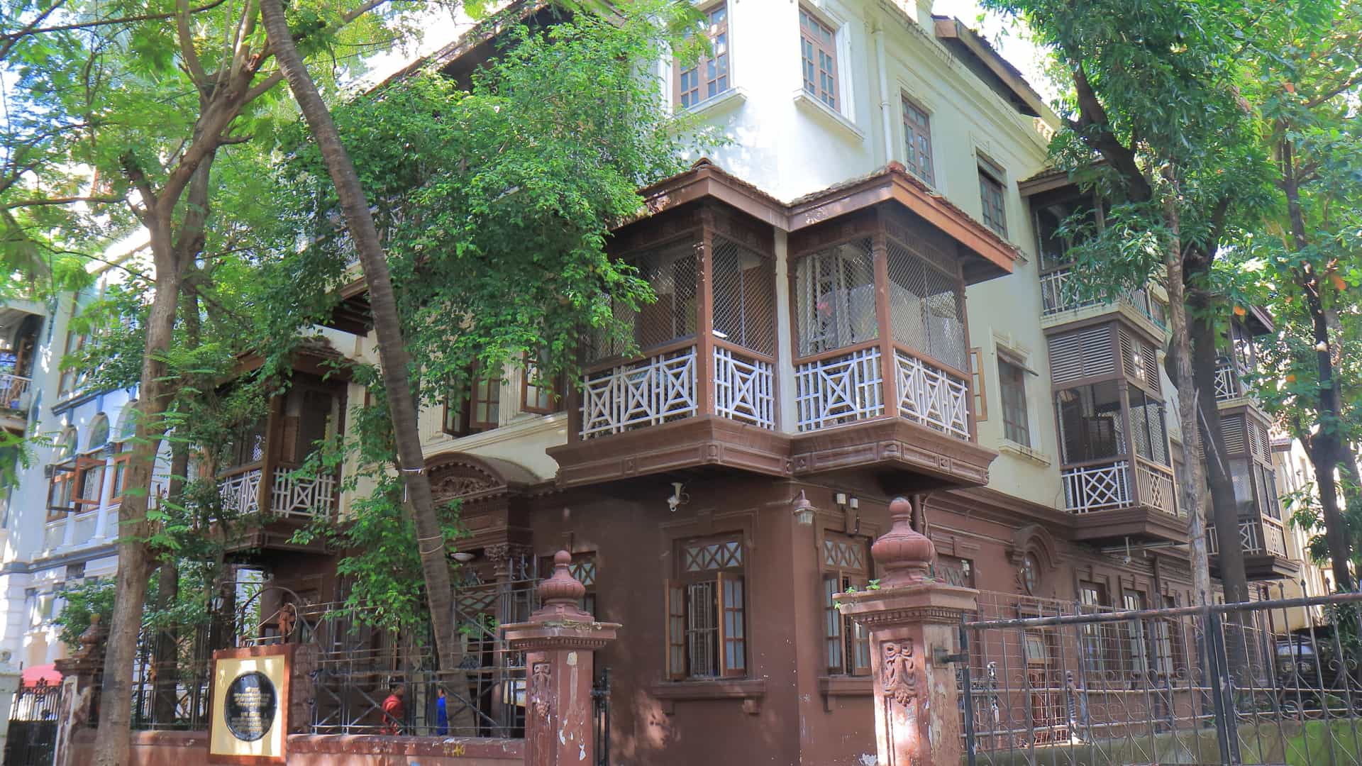 The Mani Bhavan Gandhi Museum in Mumbai, India. The image shows the exterior of a two story historical building with a balcony and a red tiled roof, surrounded by trees. This building, a former residence of Mahatma Gandhi, is now a museum and a memorial dedicated to his life and role in India's freedom movement.