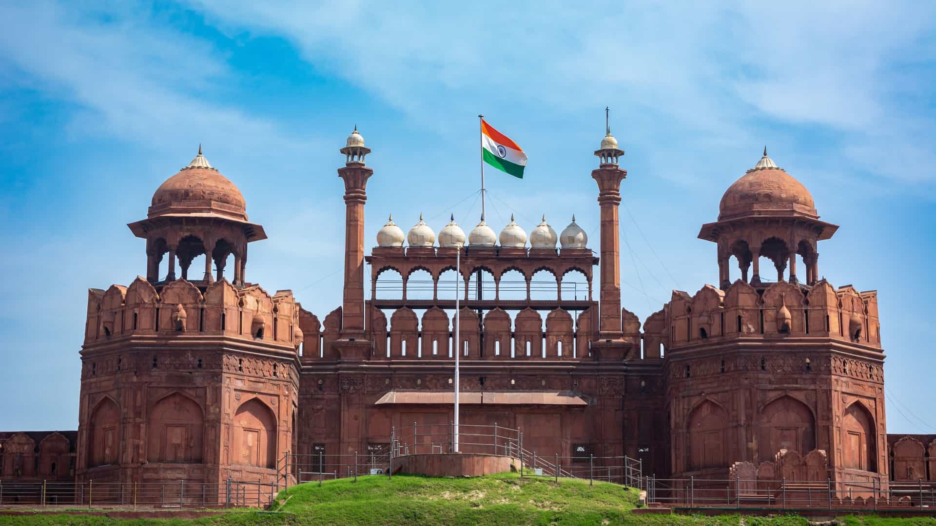 A view of the Red Fort in Delhi, India, a UNESCO World Heritage Site. The image showcases the massive red sandstone walls of the 17th century Mughal palace fort. The detailed architectural features and historical significance of the structure are highlighted, which was built by Emperor Shah Jahan.