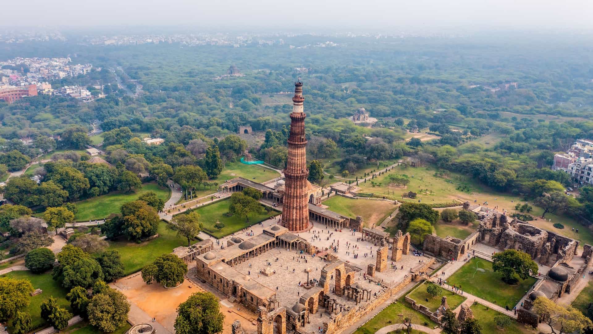A view of the Qutb Minar, a 73 meter tall minaret in Delhi, India. The tower is a UNESCO World Heritage Site, made of red sandstone and marble, with a distinct tapering shape and intricate carvings. It is a prominent example of early Indo Islamic architecture.